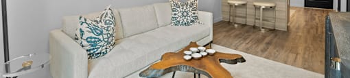a living area with a couch coffee table and a kitchen in the background