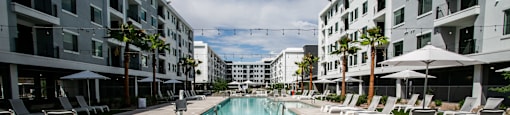 a swimming pool with lounge chairs and umbrellas in front of a building