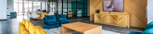 a living room with yellow couches and blue chairs and a television