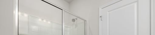 a white bathroom with a shower and a door at Ashford Townes Apartments, North Carolina