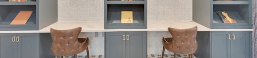 A room with grey bookshelves and two chairs.