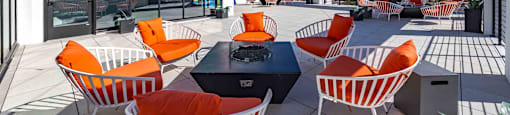 A patio with orange chairs and a table with a speaker on it.