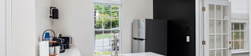 a kitchen with a white counter top, a sink, and a refrigerator
