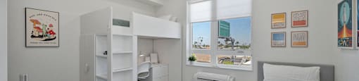 a bedroom with a bunk bed and a desk and a window