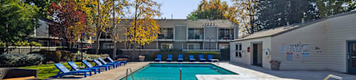 A large outdoor swimming pool surrounded by trees and a building.