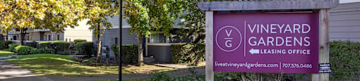 A sign for Vineyard Gardens leasing office is displayed in front of a building.