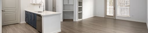 an empty living room with a kitchen and a door to a closet