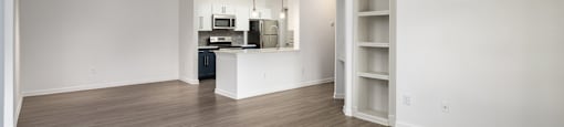 an empty living room and kitchen with wood flooring and a ceiling fan