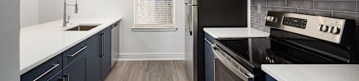 a kitchen with black appliances and white counter tops and blue cabinets