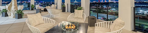 the terrace has a fireplace and a view of the city at night