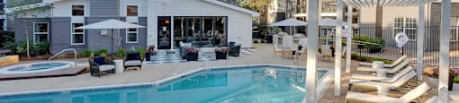 A large outdoor swimming pool with sun loungers and a pergola.