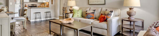 a living room with a couch table and chairs and a kitchen in the background  at Castilian Apartments, Orlando, FL, 32839