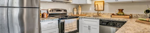 a kitchen with white cabinets and stainless steel appliances  at Castilian Apartments, Florida