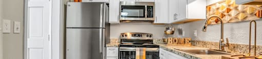 a kitchen with white cabinets and stainless steel appliances  at Castilian Apartments, Florida