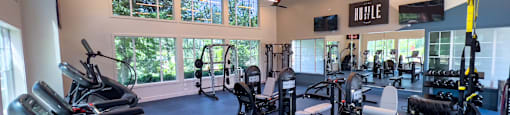 a large fitness room with cardio equipment and windows