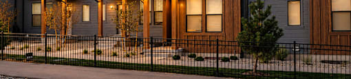 A row of modern houses with lit windows and doors.