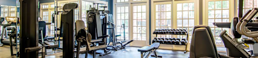 a fitness room with cardio equipment and windows