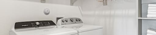 a white washer and dryer in a laundry room with shelves