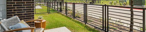 a patio with chairs and a fence and a train track