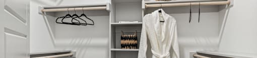 a walk in closet with a white robe and shelves