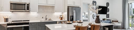 an open kitchen and dining area with stainless steel appliances and white cabinets