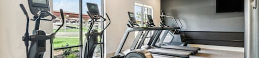 the gathering atrium gym with cardio equipment and a tv