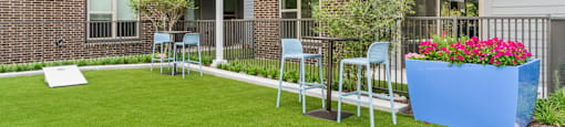 a yard with a table and chairs in front of an apartment building