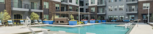 an apartment swimming pool with chairs in front of an apartment building