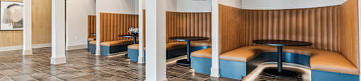 a lounge area with benches and tables in a room with pillars
