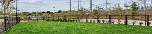 a yard with a fence and green grass and electricity poles