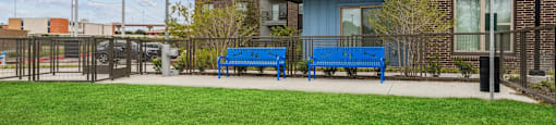 two blue benches in front of an apartment building with a green lawn