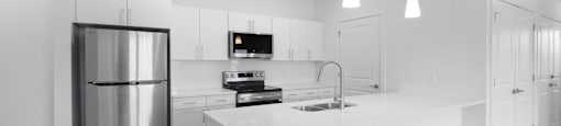A modern kitchen with a stainless steel refrigerator and white cabinets.
