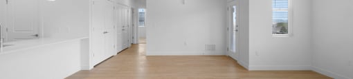 A spacious room with wooden floors and white walls.