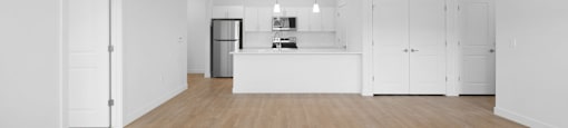 A spacious room with wooden floors and white walls.