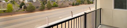 A balcony overlooks a road with houses and a mountain in the distance.