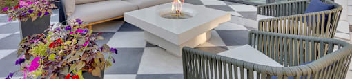 A patio area with a checkered floor, a fire pit, and chairs.