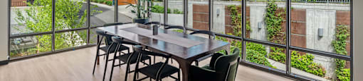 A dining table with chairs in front of a glass wall with a view of a building.