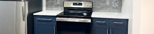 a kitchen with blue and white cabinets and stainless steel appliances