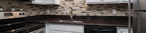 A kitchen with white cabinets and a black dishwasher.