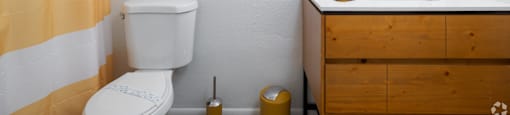 A bathroom with a toilet, sink, and striped shower curtain.