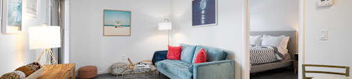 A living room with a blue couch and a wooden cabinet.