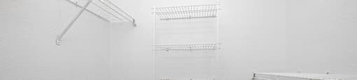 Empty white walk in closet with shelves.