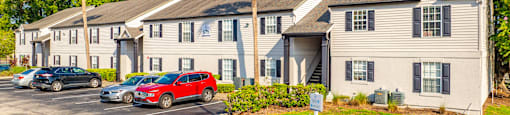 A row of houses with cars parked in front.