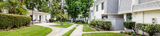 a street view of a white apartment with a gray roof and manicured lawns