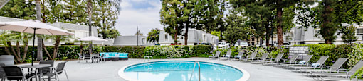 pool and hot tub with chaise lounge chairs and umbrella