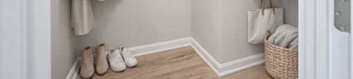 A hallway with clothes hanging and shoes on the floor.