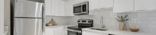 A modern kitchen with white cabinets and stainless steel appliances.