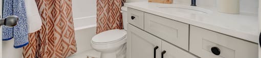 A bathroom with a toilet, sink, and shower curtain.