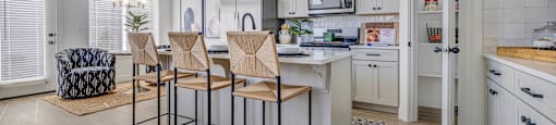A kitchen with a bar area and chairs.