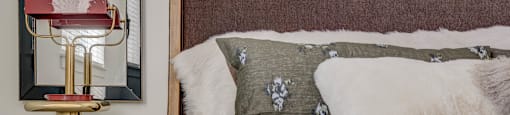 A bed with pillows and a side table with a lamp at Mt. Rainier Herriman Utah homes.